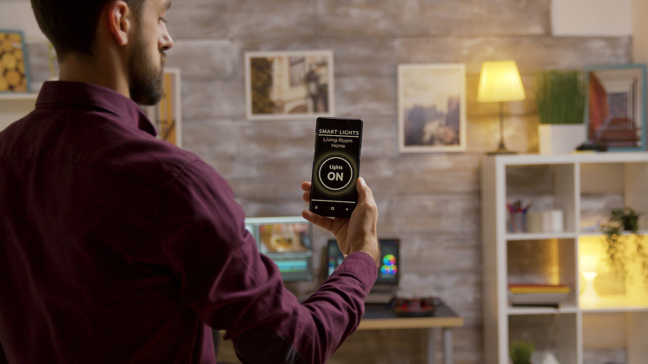 Man using a smart lights app to turn on the lights in the living room. Smart technology and application